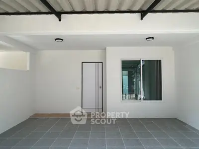 Spacious and bright empty room with exposed ceiling beams, tiled flooring, and access to a sunny balcony, ideal for personalization.