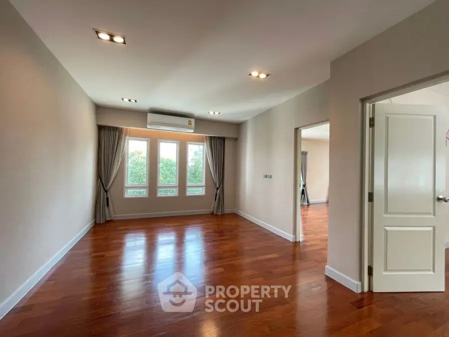 Spacious empty room with wooden floors and large windows
