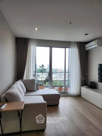 Modern living room with large window and city view, featuring cozy sofa and sleek decor.
