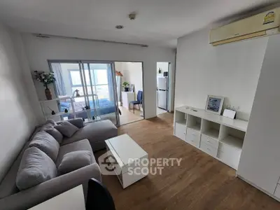 Modern living room with cozy sofa and open layout leading to bedroom and kitchen.