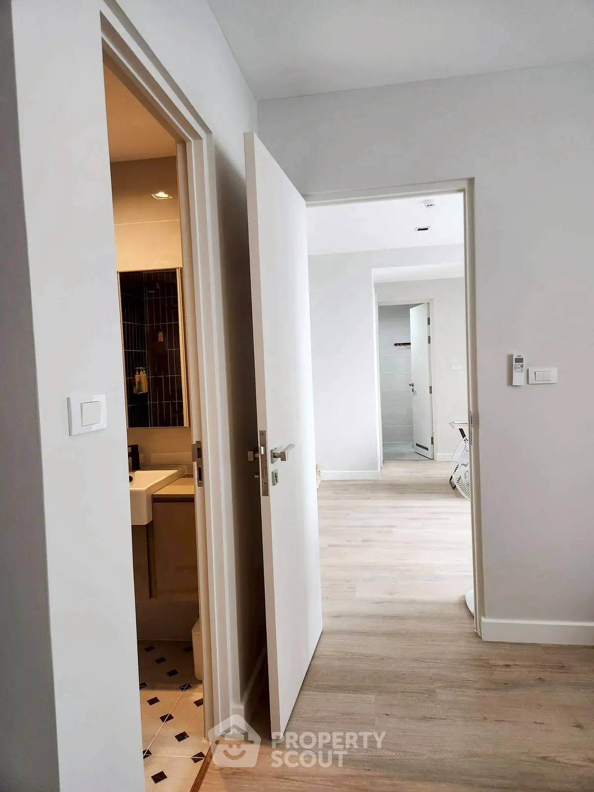 Modern apartment hallway with open doors and wood flooring