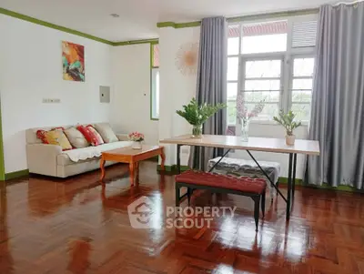 Charming living room with hardwood floors, cozy sofa, and large window view.