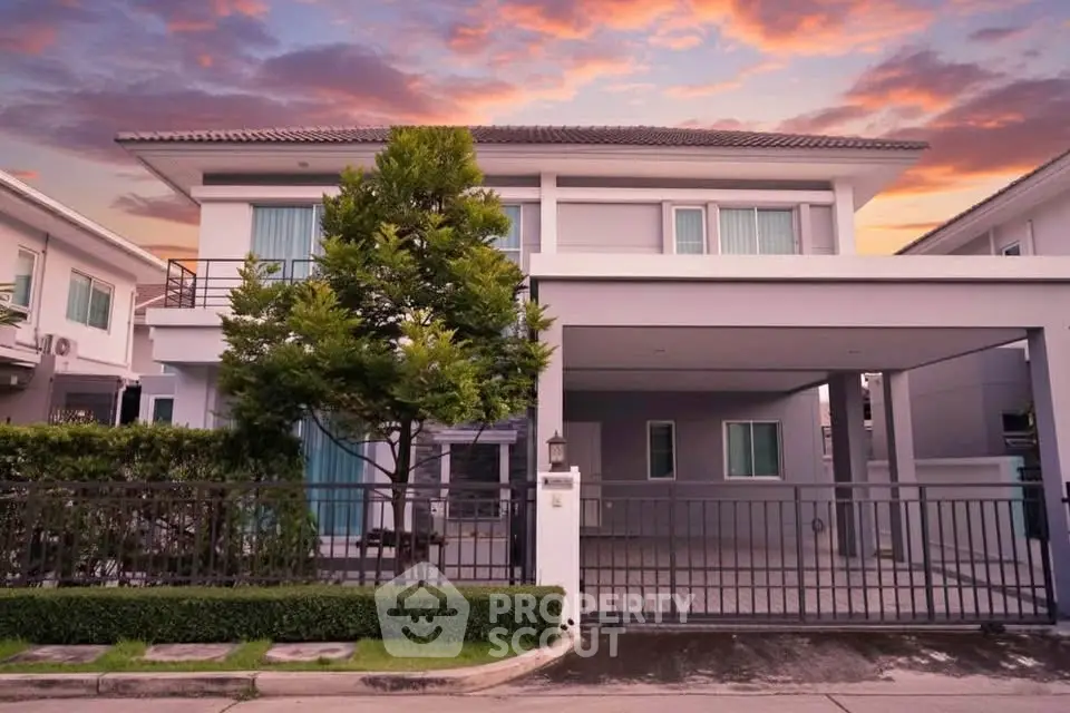 Stunning modern two-story house with spacious driveway and lush greenery at sunset.