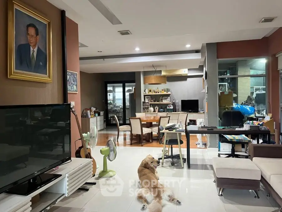 Spacious living room with modern decor and a cozy atmosphere, featuring a large TV and stylish furniture.