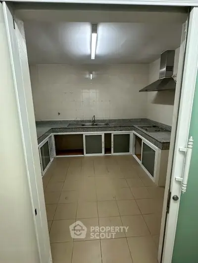 Spacious kitchen with ample counter space and modern range hood, perfect for culinary enthusiasts.