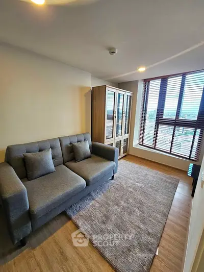 Cozy living room with modern sofa and large window offering city views