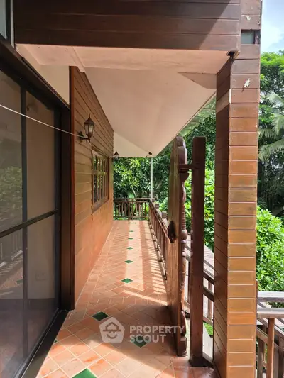 Charming wooden balcony with lush greenery view, perfect for relaxation and enjoying nature.