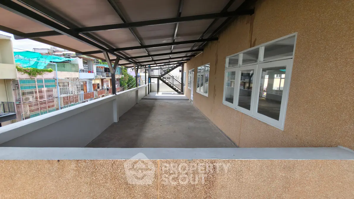 Spacious balcony with modern railing and large windows in urban residential building.