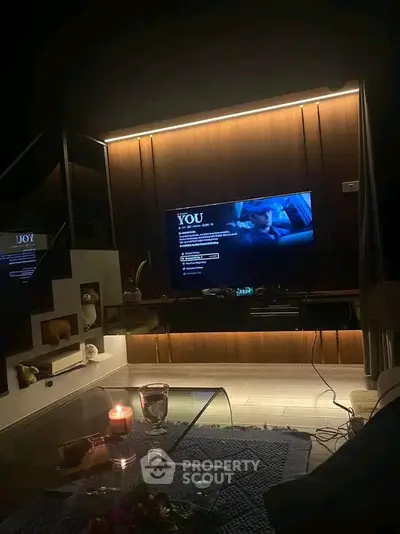 Cozy living room with modern TV setup and ambient lighting, perfect for relaxation.