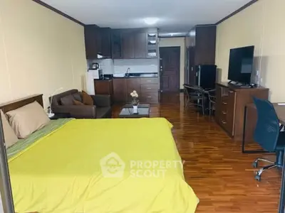 Spacious studio apartment with open layout, featuring a cozy bed, modern kitchen, and comfortable living area.