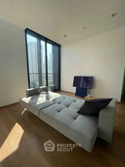Modern living room with large windows and stylish sofa in urban apartment
