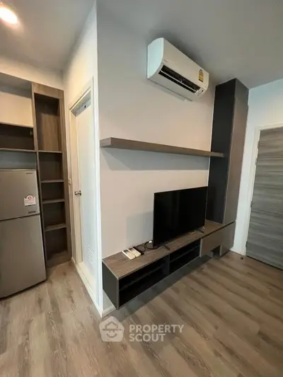 Modern living room with sleek TV setup and air conditioning in stylish apartment.