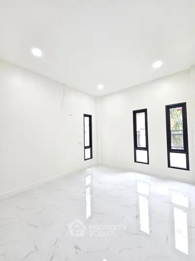 Bright and spacious empty room with modern white tile flooring and large windows.