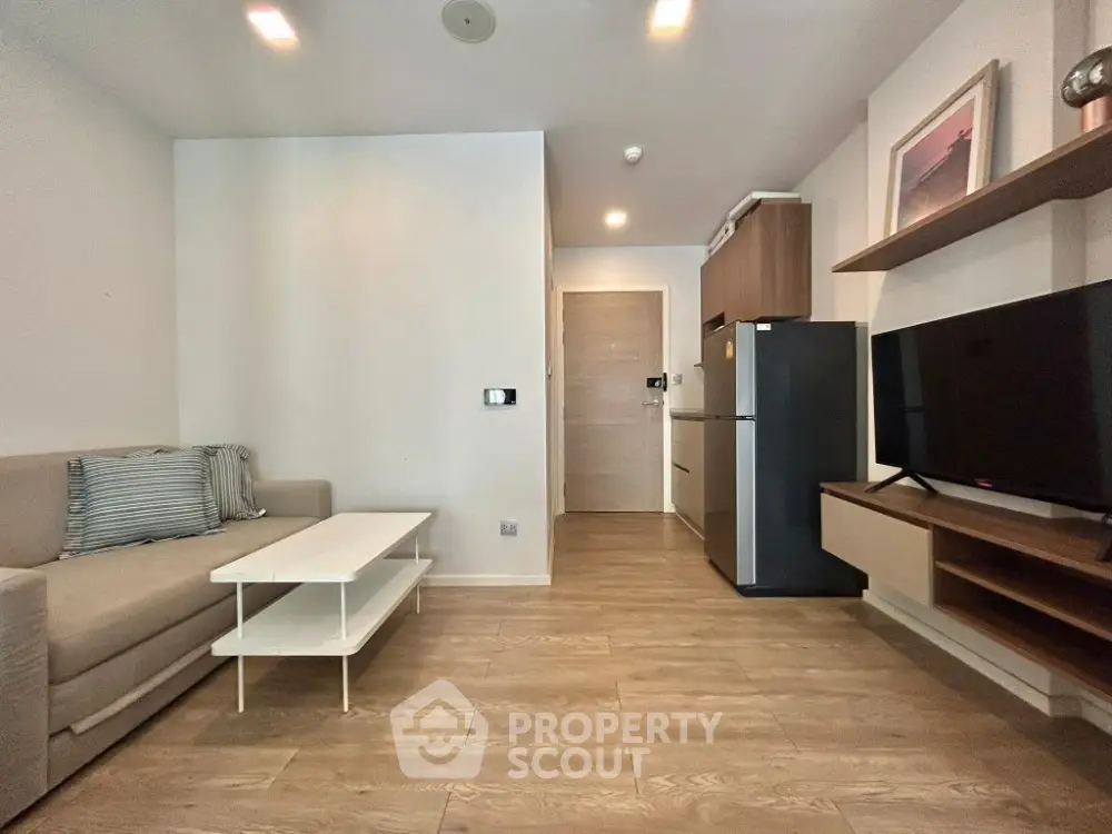 Modern living room with sleek furniture and wooden flooring, featuring a cozy sofa and a flat-screen TV.