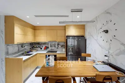Modern kitchen with wooden cabinets, marble backsplash, and dining table, featuring a sleek black fridge.