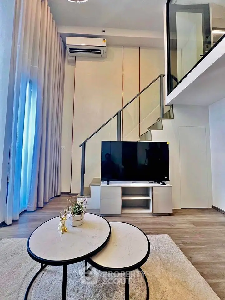 Modern duplex living room with stylish decor and large TV, featuring a mezzanine level and elegant furnishings.
