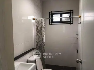 Modern bathroom with sleek white tiles and floral shower curtain