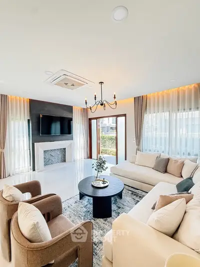 Luxurious living room with elegant decor, modern chandelier, and large windows offering natural light.