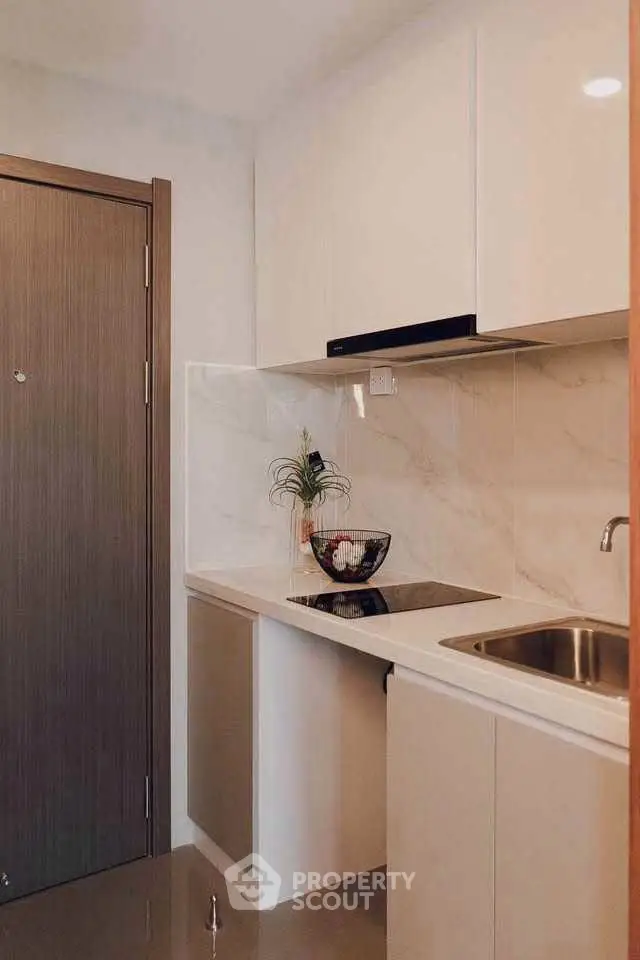 Modern compact kitchen with sleek cabinetry and marble backsplash in a stylish apartment.