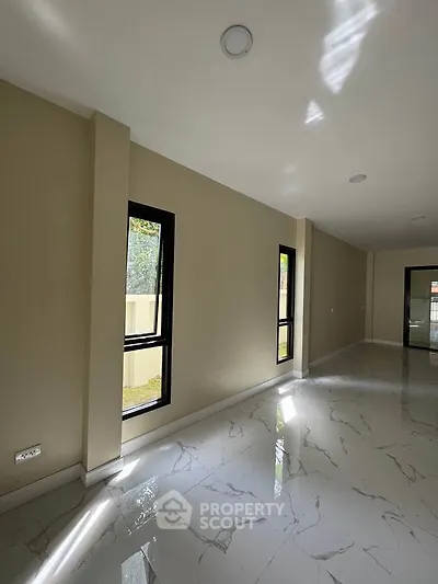 Spacious modern living room with large windows and glossy tiled flooring, offering ample natural light.