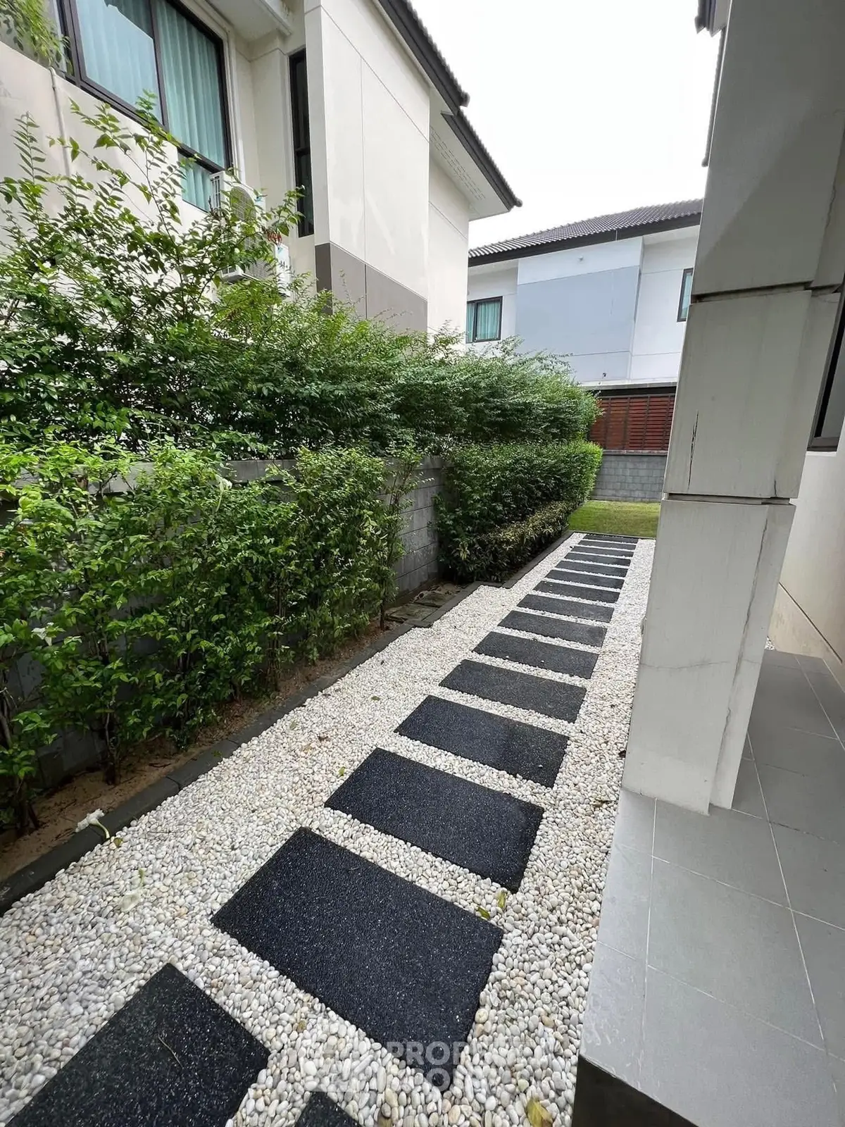 Charming garden pathway with modern stepping stones and lush greenery in a residential area.
