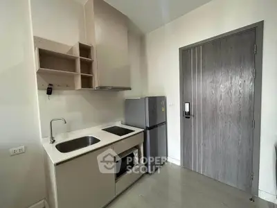 Modern compact kitchen with sleek cabinetry and stainless steel appliances in a stylish apartment.