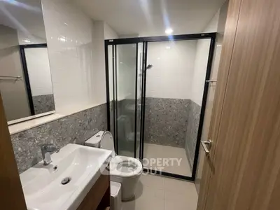 Modern bathroom with glass shower and sleek fixtures in contemporary apartment.