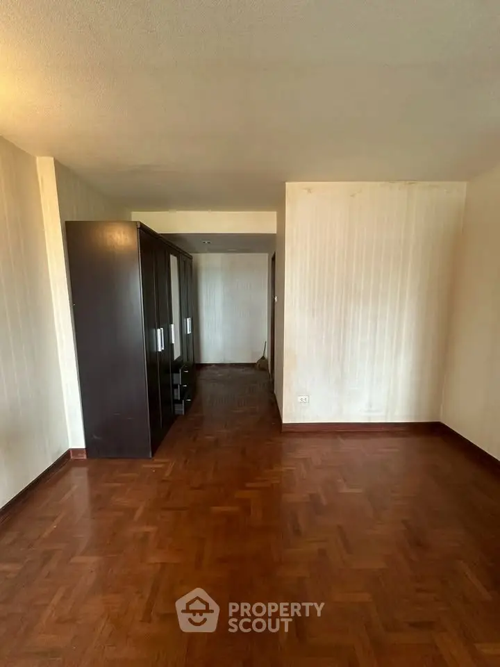 Spacious empty room with parquet flooring and built-in wardrobe