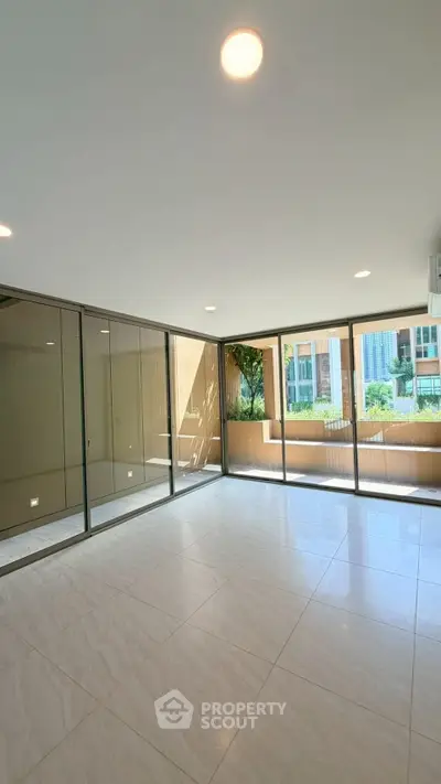 Spacious modern living room with large windows and garden view in luxury apartment.