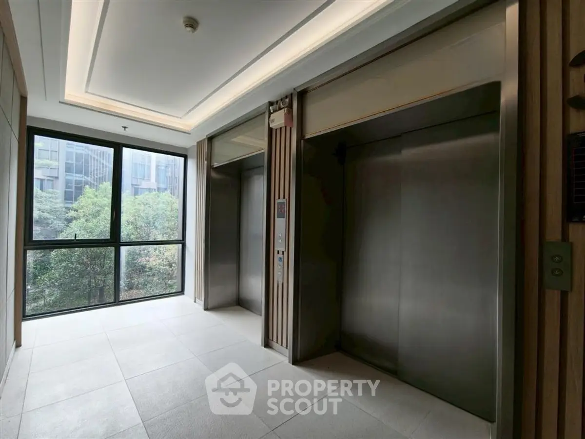 Modern building elevator lobby with large window and sleek design.