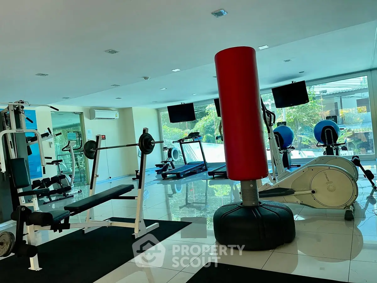 Spacious gym with modern equipment and large windows for natural light