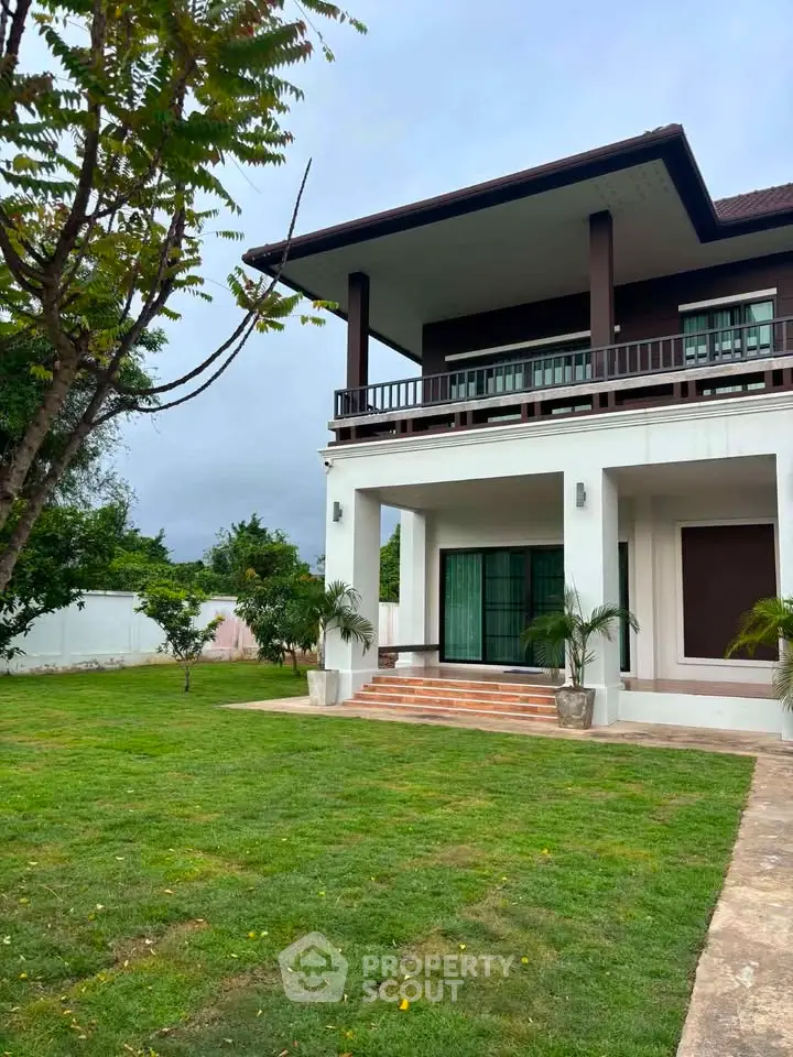 Stunning two-story home with lush green lawn and elegant balcony, perfect for family living.