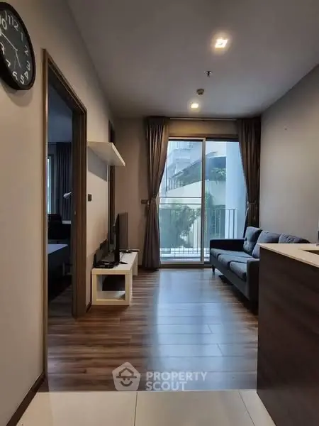 Modern living room with wooden flooring and balcony view in stylish apartment.