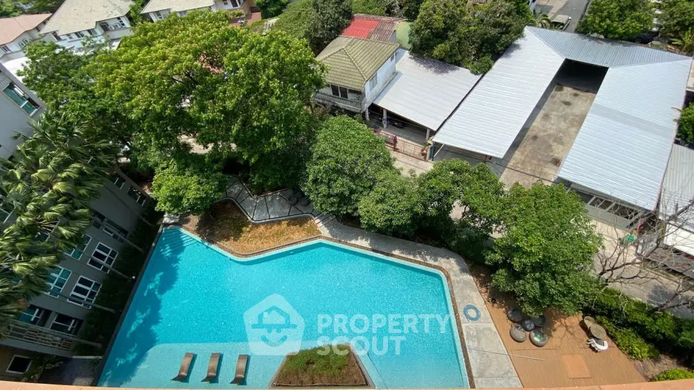Stunning aerial view of a luxurious swimming pool surrounded by lush greenery and modern buildings.