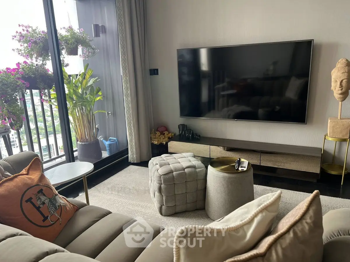 Stylish living room with modern decor and balcony view, featuring a large TV and plush seating.