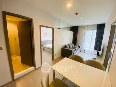 Modern apartment interior with open living and dining area, featuring a cozy sofa and natural light.