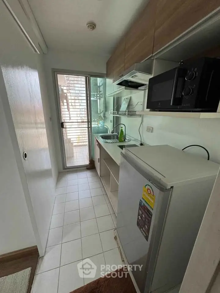 Compact kitchen with modern appliances and access to balcony, ideal for urban living.