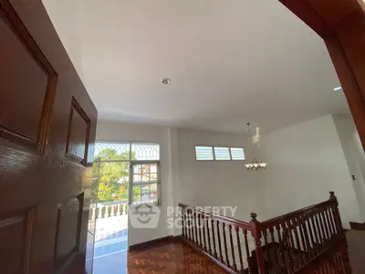 Spacious interior with wooden railing and large windows offering natural light