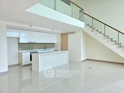 Modern open-plan kitchen with sleek design and staircase in luxury apartment