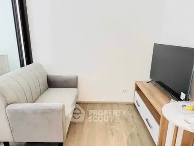 Modern living room with sleek sofa and flat-screen TV on wooden stand.