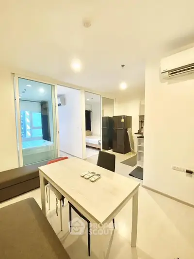 Modern apartment interior with open layout, featuring dining area, living space, and visible bedroom.