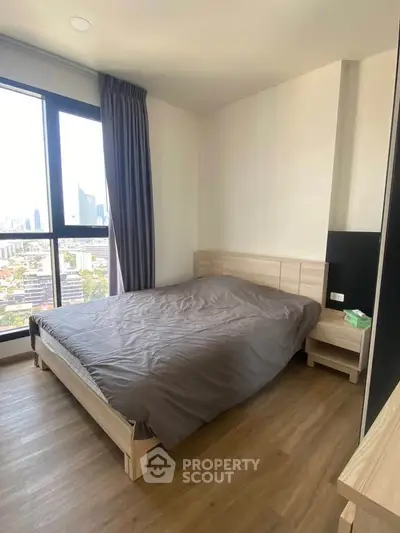 Modern bedroom with city view and wooden flooring in high-rise apartment