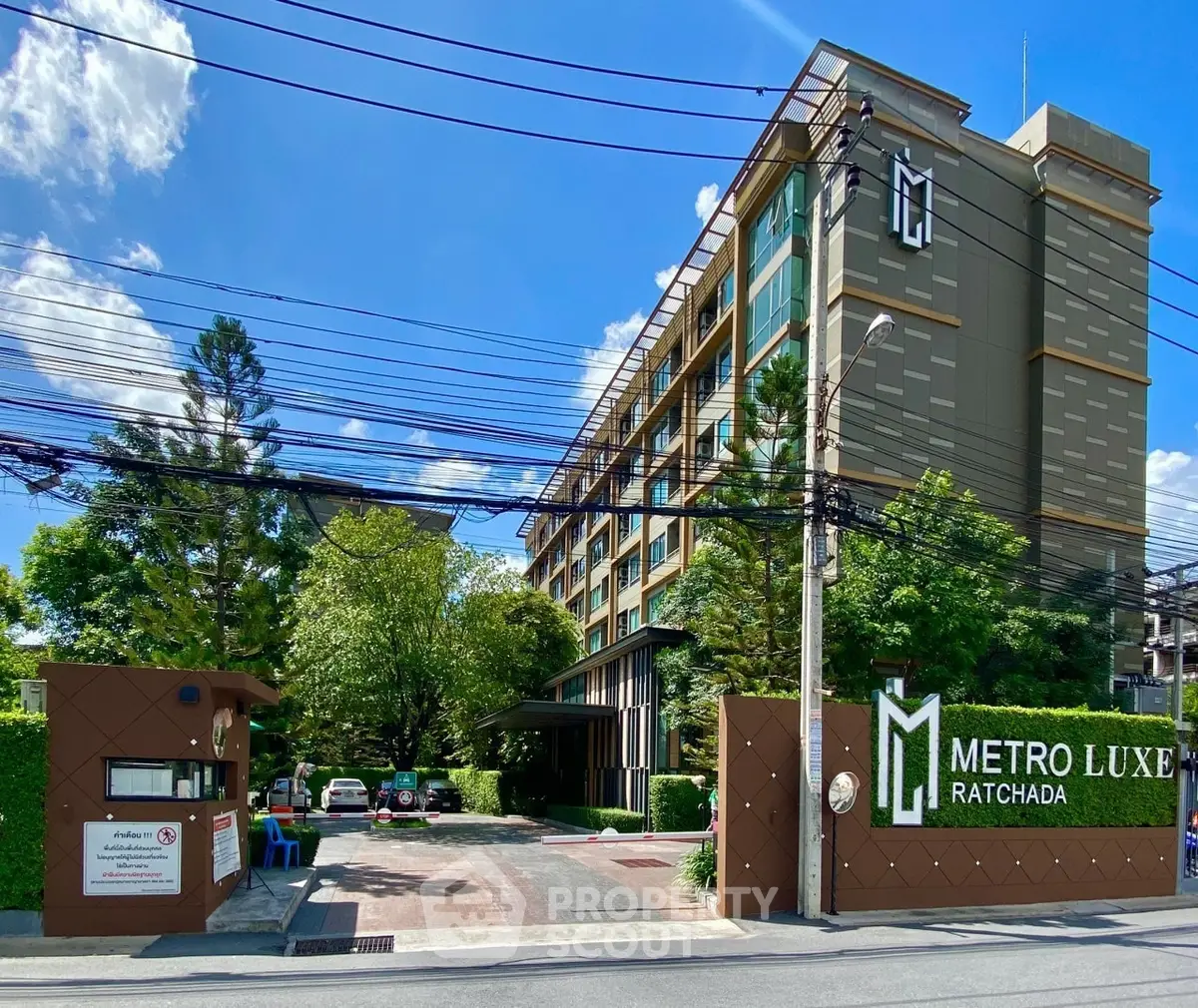 Modern condo building with lush greenery and secure entrance in vibrant urban area.