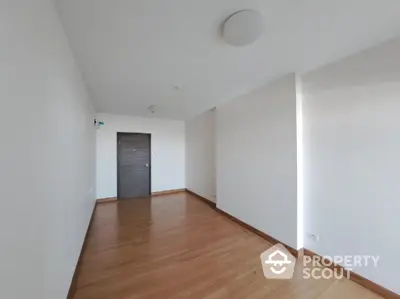 Spacious and well-lit empty living room with polished hardwood flooring and pristine white walls, ready for personalization.