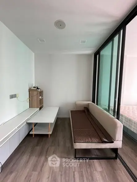 Modern living room with sleek furniture and glass partition, featuring a cozy sofa and stylish wooden flooring.