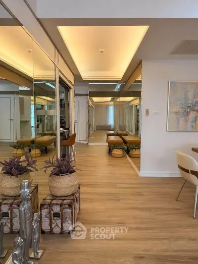 Elegant living room with mirrored walls and stylish decor, featuring wooden flooring and modern furniture.
