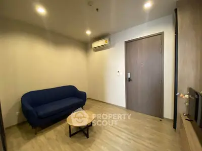 Modern living room with blue sofa, wooden flooring, and air conditioning unit.