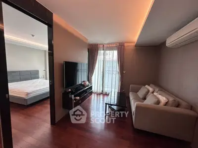 Modern apartment living room with cozy sofa and flat-screen TV, adjacent to a stylish bedroom.