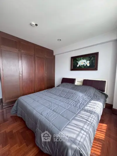 Spacious bedroom with elegant wooden flooring and large wardrobe, perfect for comfortable living.