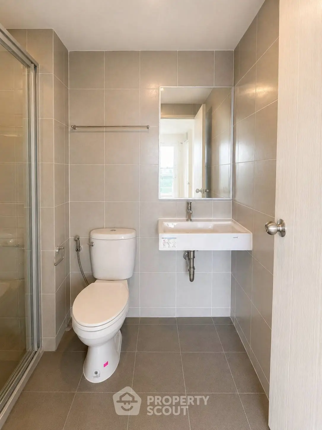 Modern bathroom with sleek design, featuring a shower, toilet, and wall-mounted sink.